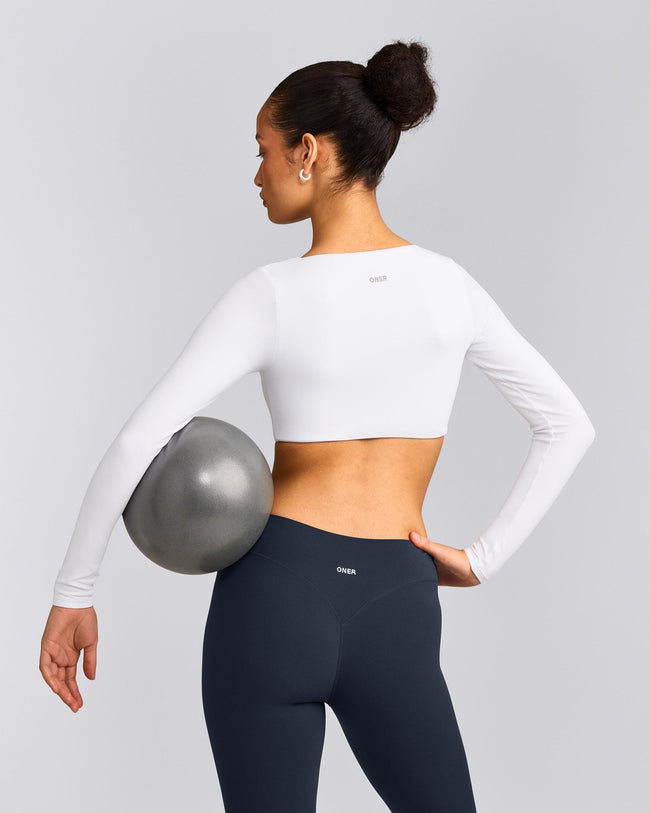 SoftMotion™ Scoop Neck Long Sleeve Crop Top with Built in Bra Shelf with Grey Logo | White
